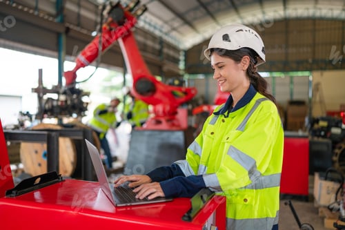 Preview: Portrait of female automation engineer using laptop and looking camera in industrial factory.