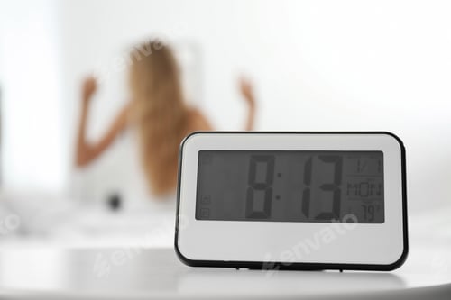 Preview: Digital alarm clock and blurred woman on background. Time of day