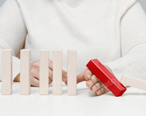 Preview: Hand stops the fall of wooden blocks on a white background.