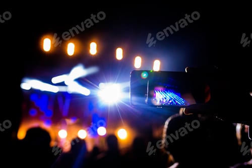 Preview: crowd of people enjoying night performance,unrecognizable people dancing with hands raised. Concert