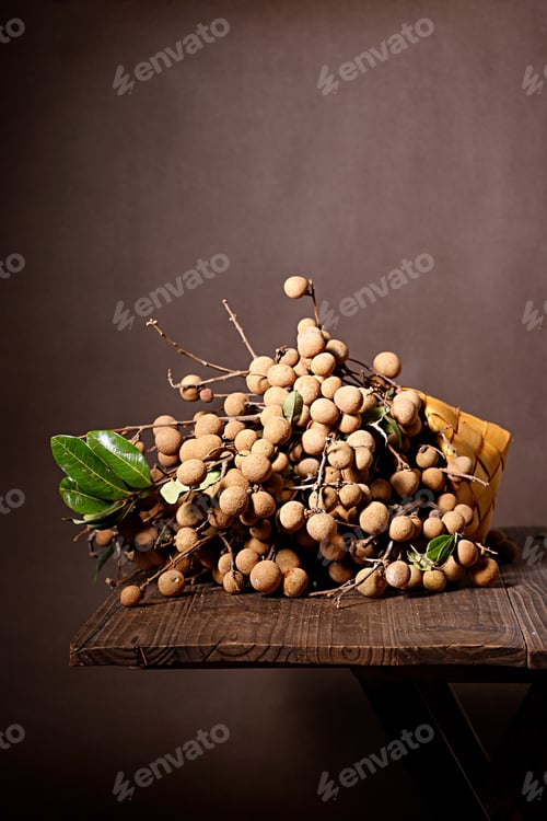 Preview: Vertical closeup of longan on the wooden table isolated on brown background.
