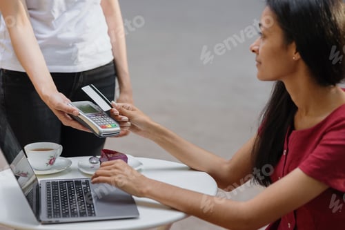 Preview: female hands hold a bank card to pay for coffee or dinner in a restaurant or for shopping in a store