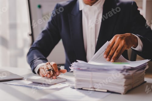 Preview: work from office A businessman works a bunch of paper files to find information on his desk at home.