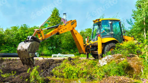 Preview: Excavator with bucket in the field among a grass