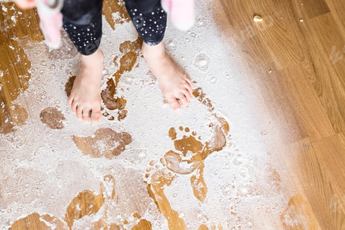 Preview: Low section of girl standing on flour covered floor at home
