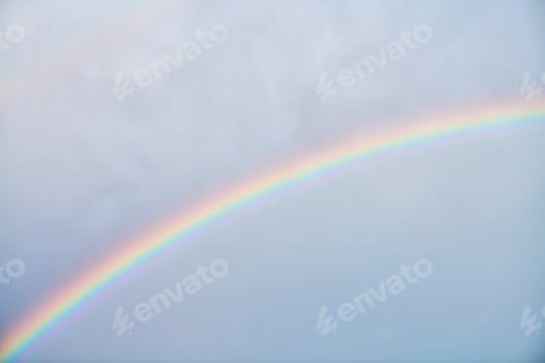 Preview: Gentle rainbow arching across soft blue sky