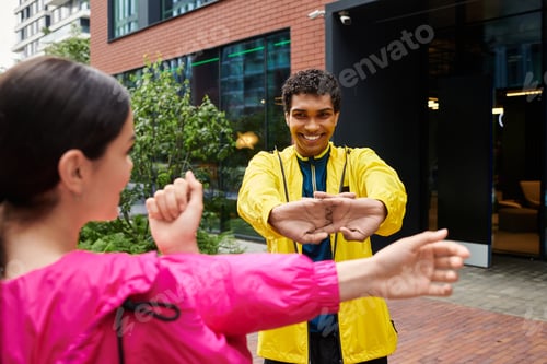 Preview: Young athletes engage in stretching exercises outdoors in an urban setting while smiling