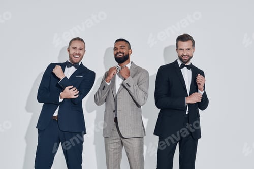 Preview: Three handsome young men in suits and bowties looking at camera and smiling