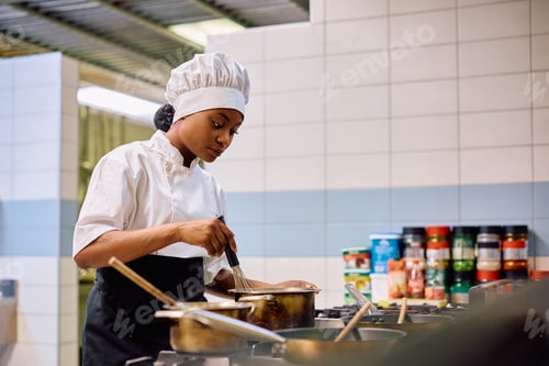 Preview: Black female cook preparing food while working in a restaurant.