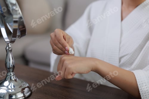 Preview: Woman applying moisturizing cream on her hands after shower