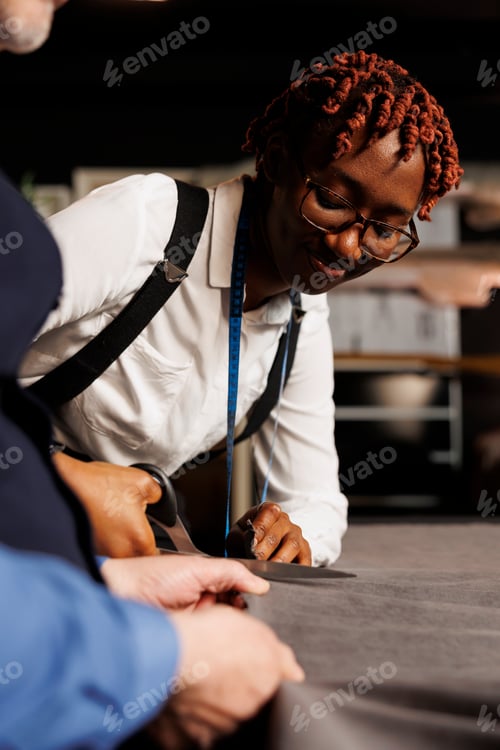 Preview: Tailor teaching apprentice to cut fabric