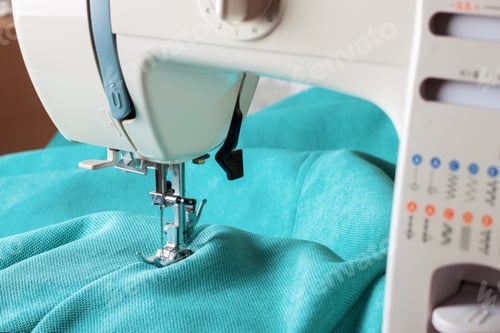 Preview: Close up of sewing machine working with turquoise fabric