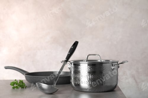 Preview: Set of clean cookware on table against color background. Space for text