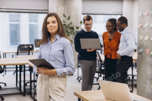 Preview: Businesswoman holding tablet smiling with multi ethnic colleagues working together using laptops