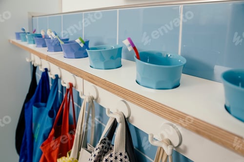 Preview: Line-up of of toothbrushes and bags on hooks in kindergarten
