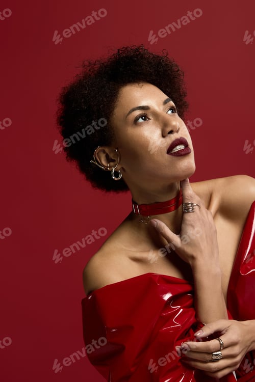 Preview: Elegant young woman in striking red attire against a bold background captivates with poise