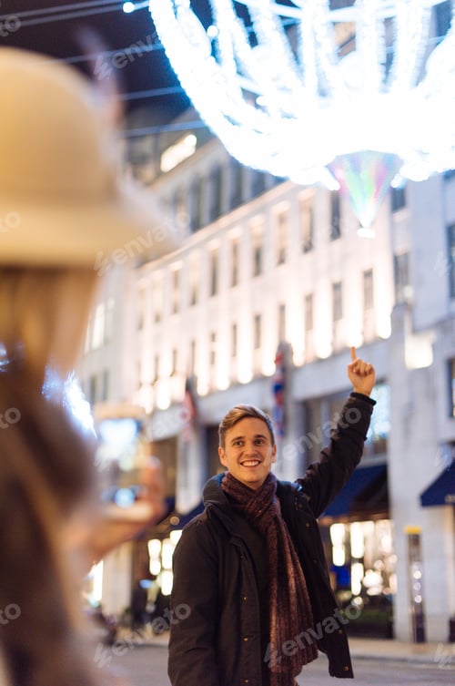 Preview: Young couple pointing to xmas lights on New Bond street, London, UK