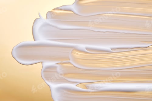 Preview: Swatch with white cream texture on a golden background.