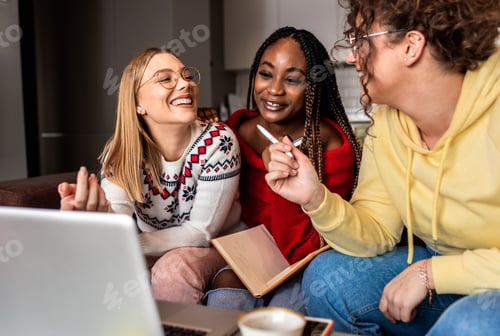Preview: Diverse group female students learning at home using laptop and books.