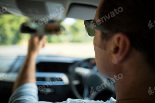 Preview: Man adjusting rearview mirror in car