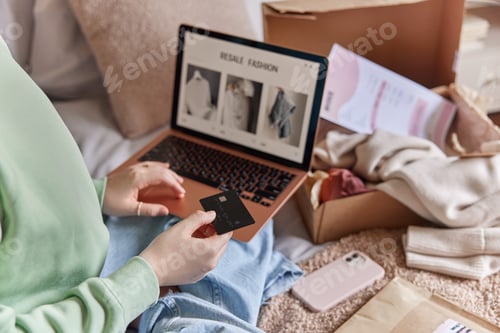 Preview: Unrecognizable person holds banking card and uses laptop computer makes shopping online buys new