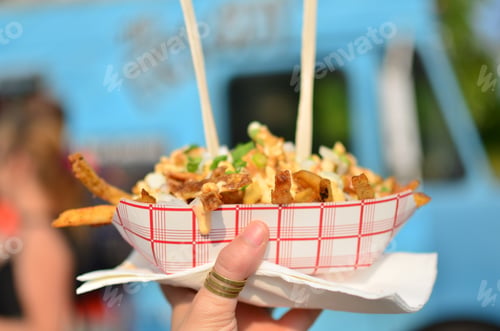 Preview: Loaded fries being held up in front of a food truck