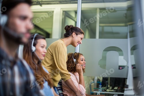 Preview: Female customer service executive interacting with her colleague at desk