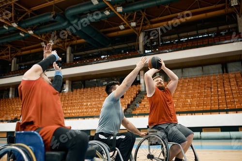 Preview: Player in wheelchair taking a shot on while rivals are trying to block him during basketball match.