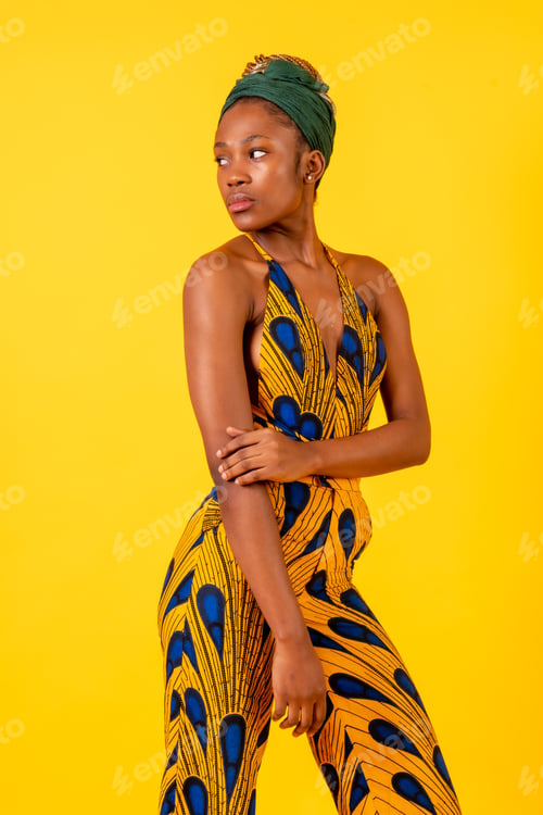 Preview: African young woman in the studio on a yellow background, portrait in a traditional costume looking