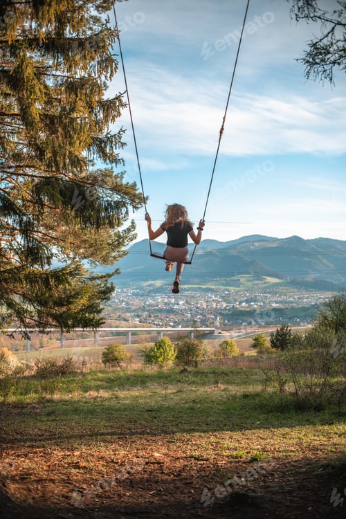 Preview: Rearview of a young woman on a tree swing in Slovakia