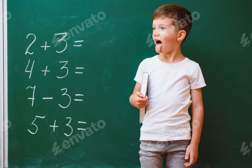Preview: Funny schoolboy near the green school board in the classroom. Elementary school. Back to school.