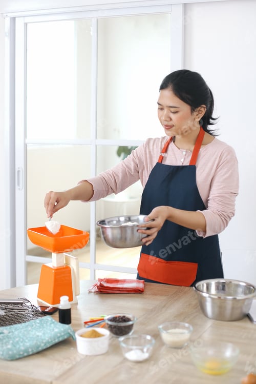 Preview: Cheerful Young Asian Woman Measuring Flour Into Gram Meter