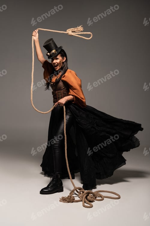 Preview: full length view of beautiful screaming steampunk woman holding lasso on grey