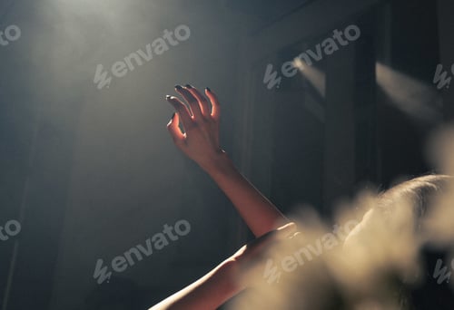 Preview: Closeup of the hand of a woman covering the lights with a dark blurry background