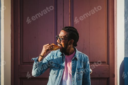 Preview: Young man biting a cheeseburger on the street