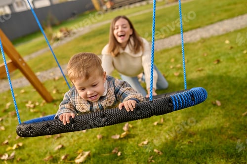 Preview: Woman pushing swing with joyful child