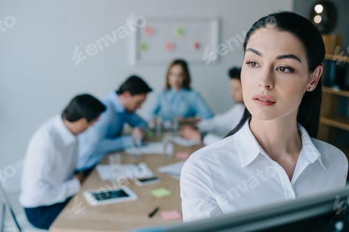 Preview: selective focus of pensive businesswoman and colleagues behind at workplace in office
