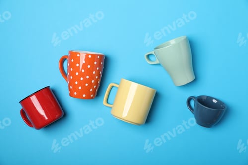 Preview: Many colorful cups on light blue background, flat lay