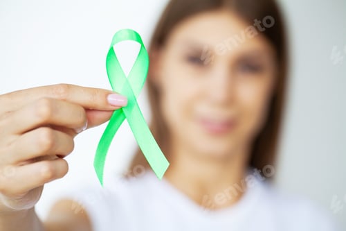 Preview: Green ribbon in hand as symbol to awareness Lymphoma cancer
