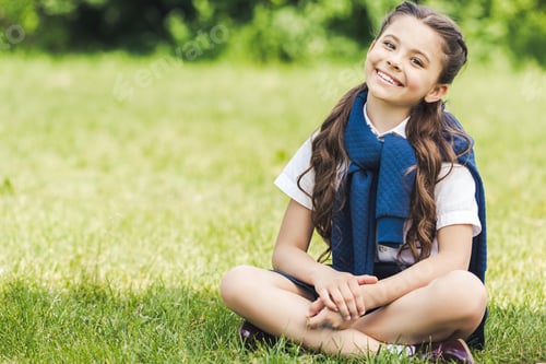 Preview: beautiful preteen schoolgirl sitting on grass in park