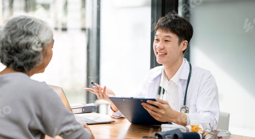 Preview: Asian male doctor consulting senior old patient filling form at consultation.