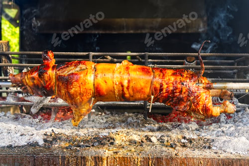 Preview: Whole pig spit roasted. Pig roasted on a barbecue spit. Outdoor Barbecue grill in open bbq pit.