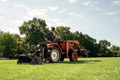Preview: Loan work. Man is with utility tractor with grass cutter and aerator equipment on the field