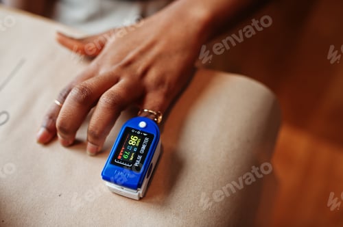 Preview: African american women with pulse oximeter on hand measuring oxygen saturation level.