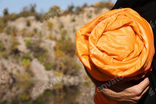 Preview: Man with orange sleeping bag outdoors, closeup. Space for text