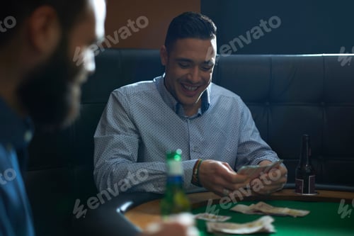 Preview: Male friends playing card game for cash at pub card table