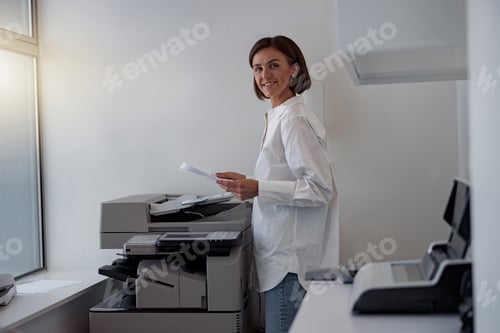 Preview: Smiling woman worker scanning a document on photocopy machine In modern office