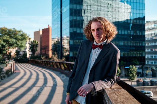 Preview: Stylish man standing on a bridge outdoors.