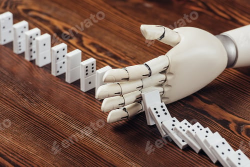 Preview: selective focus of robotic hand preventing dominoes from falling on wooden desk