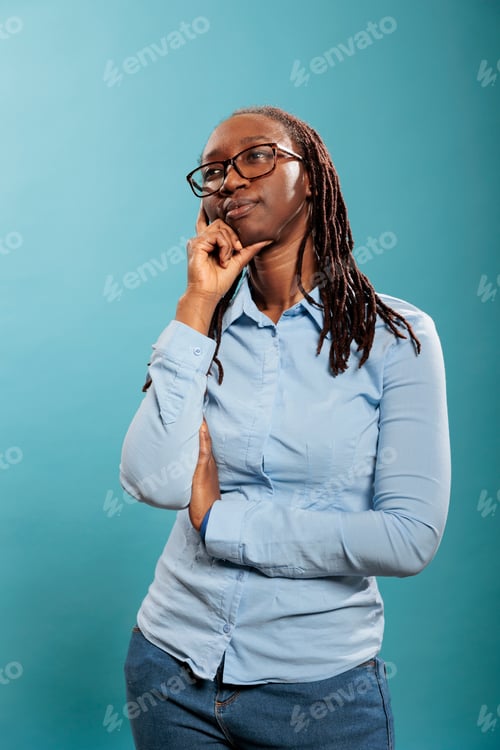 Preview: Pensive thoughtful african american woman being meditative and introspective on blue background.